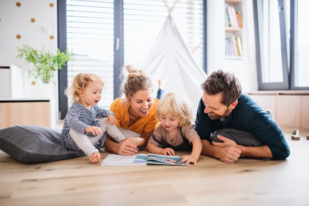 Family reading together on the floor, with children and cozy decor.